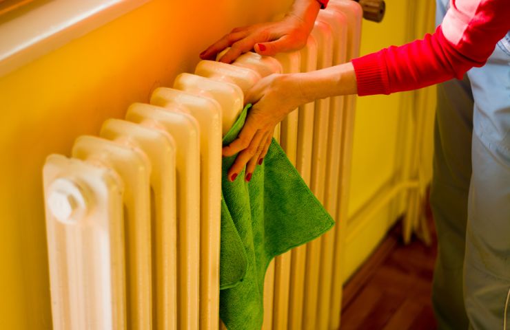 donna che pulisce il termosifone con un panno